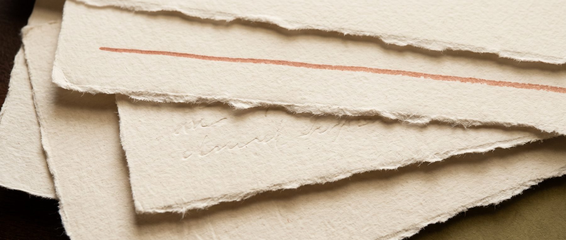 Un papier à bords frangés déchiré, marqué d'un unique trait terre cuite.